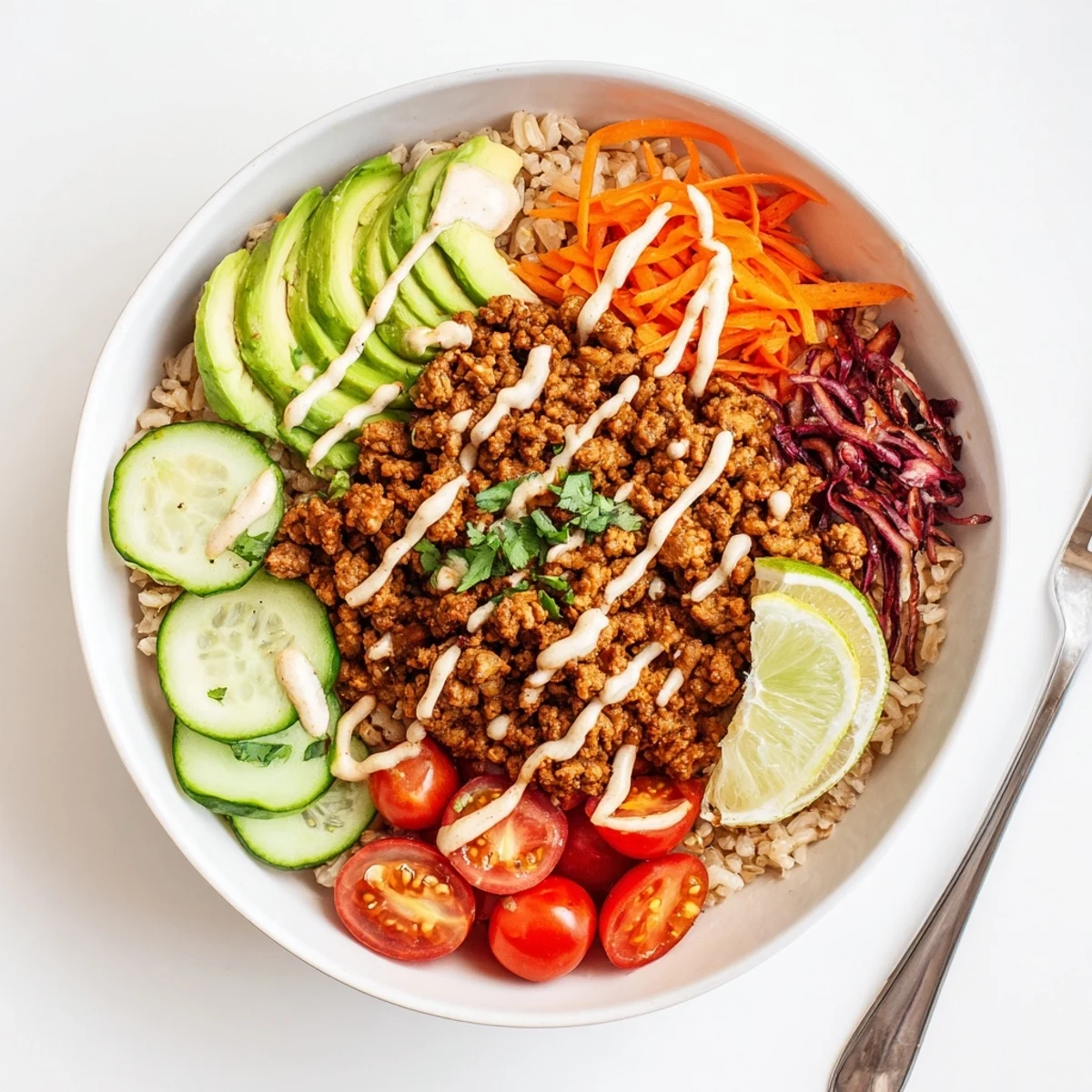 A colorful plant-based meat bowl topped with fresh veggies and creamy sauce.  