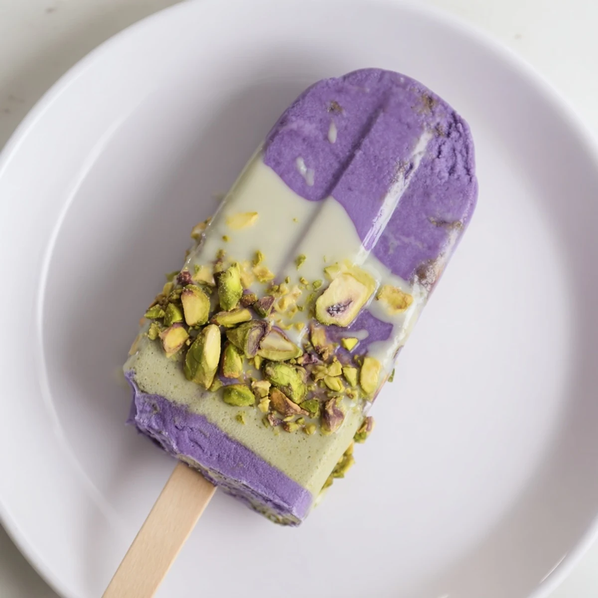 Creamy ube and pistachio ice cream bars drizzled with sweetened condensed milk, vibrant treat.  