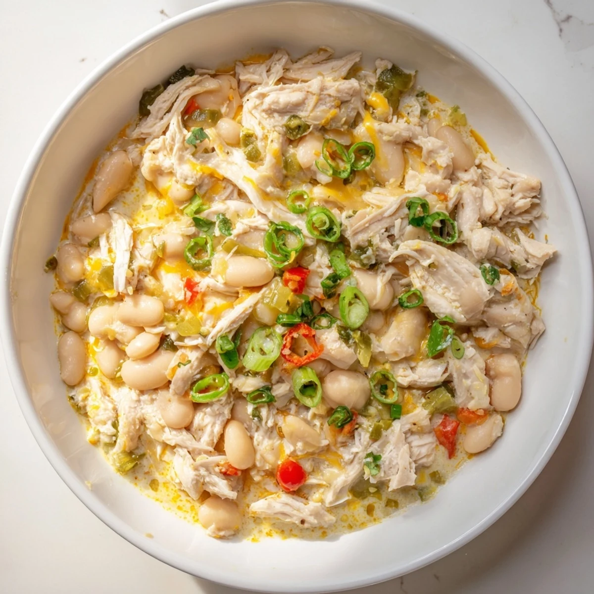 Picture a steaming bowl of creamy white chicken chili with beans, garnished with fresh cilantro and cheese.