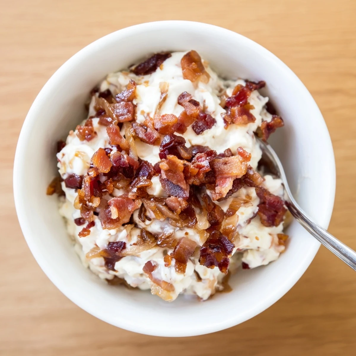 Golden caramelized onion and bacon dip, a creamy, savory appetizer ready for dipping.