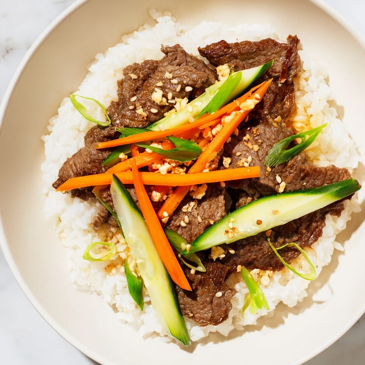 Bulgogi Beef Bowl: Tender, glistening beef atop fluffy rice with colorful vegetables, a delicious Korean meal.