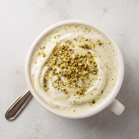 Creamy pistachio milk latte topped with crushed pistachios, perfect for coffee lovers.  
