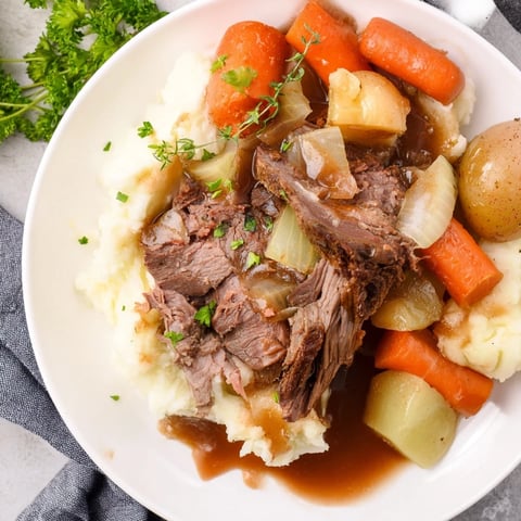 Slow Cooker Pot Roast with Mashed Potatoes served with rich gravy and vibrant vegetables.