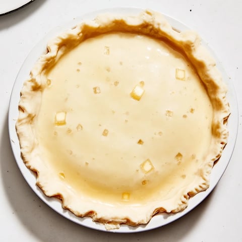 Golden, flaky Water Pie sits in a pie plate, a creamy, sweet dessert perfect for any occasion.