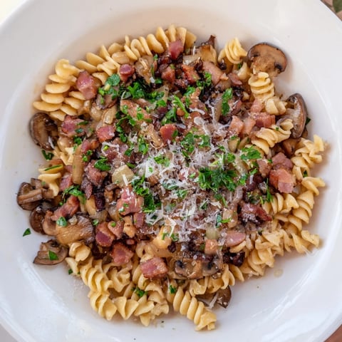 Fusilli with Bacon, Onions, and Mushrooms, a steaming pasta dish with crispy bacon crumbles.