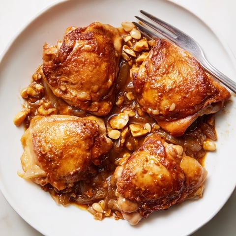Close-up of Budget Fesenjan Stew with dark, tender chicken thighs and a rich, glossy sauce.