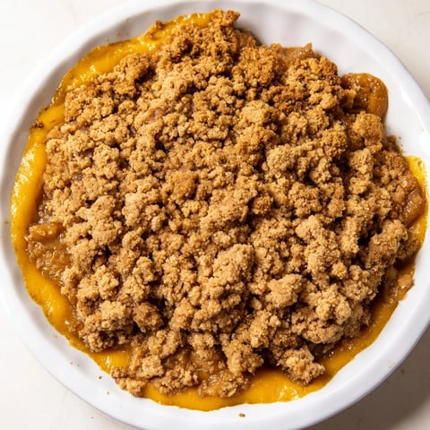 Warm pumpkin crisp bubbling with a golden brown crumble, a comforting autumn dessert.