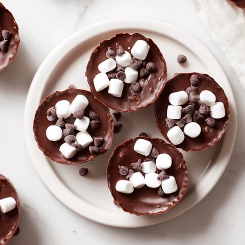 Melted chocolate cradles hot cocoa mix and mini marshmallows in a hot cocoa bomb cup.