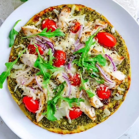 Golden, bubbly Pesto Chicken Flatbread with mozzarella, tomatoes, and red onion, ready to eat.