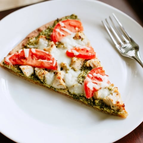 Golden-brown Chicken Pesto Pizza with melted mozzarella, fresh basil, and juicy tomato slices on a thin, crisp crust.