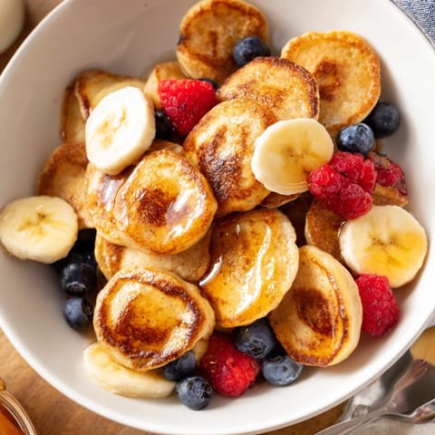 Delightful mini pancake cereal in a bowl, perfect for breakfast with milk.  