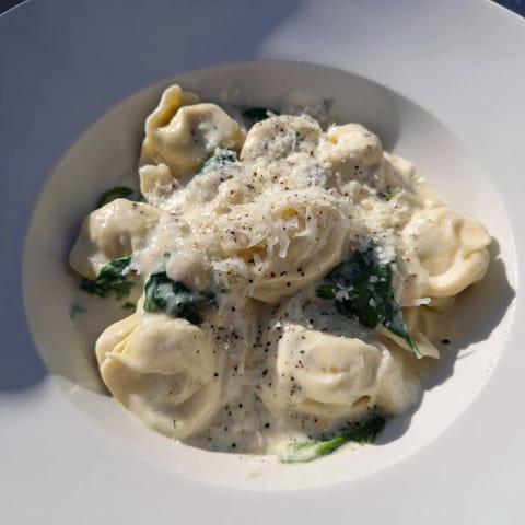 Creamy Spinach Alfredo Tortellini, with vibrant green spinach nestled in cheesy, velvety Alfredo sauce.