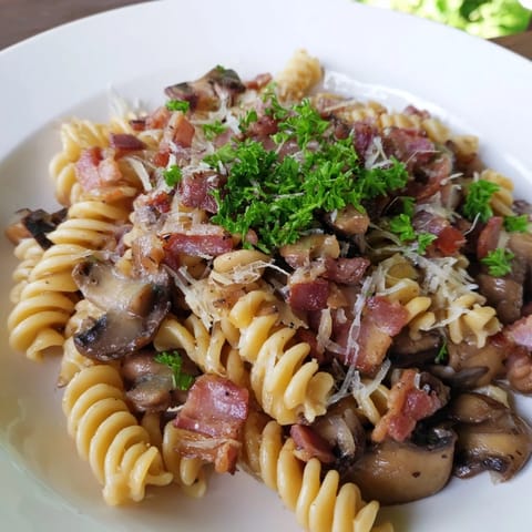 This photo features a generous serving of Fusilli with Bacon, Onions, and Mushrooms, ready to enjoy.