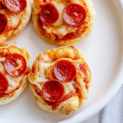 A close-up of delicious, crispy Mini Pepperoni Pizza Pinwheels with visible pepperoni slices and bubbly cheese.