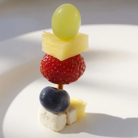 Vibrant Christmas Light Fruit Skewers feature bright red strawberries, green grapes, and sweet pineapple chunks.