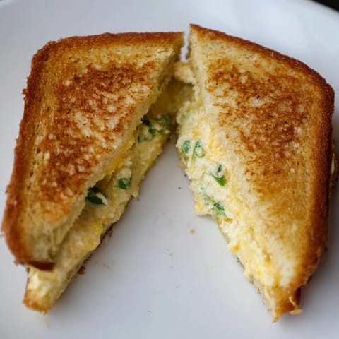 Spicy jalapeño popper grilled cheese oozing warm melted cheese, served beside a steaming bowl of tomato soup.