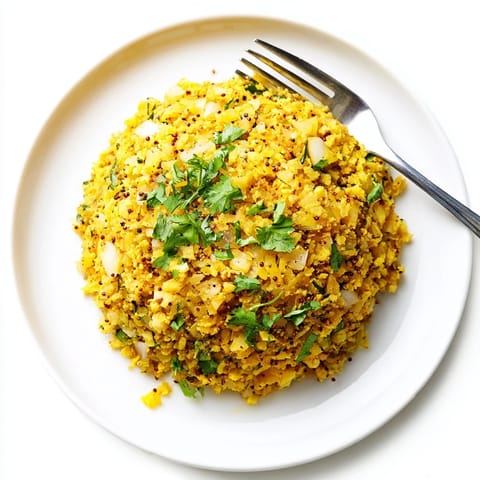 Golden Turmeric Cauliflower Rice served warm in a white bowl, garnished with fresh cilantro and a lemon wedge for a bright, zesty finish.