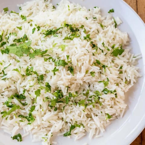 Tender grains of Cilantro Lime Rice mixed with chopped cilantro and lime, served alongside grilled chicken and black beans.  