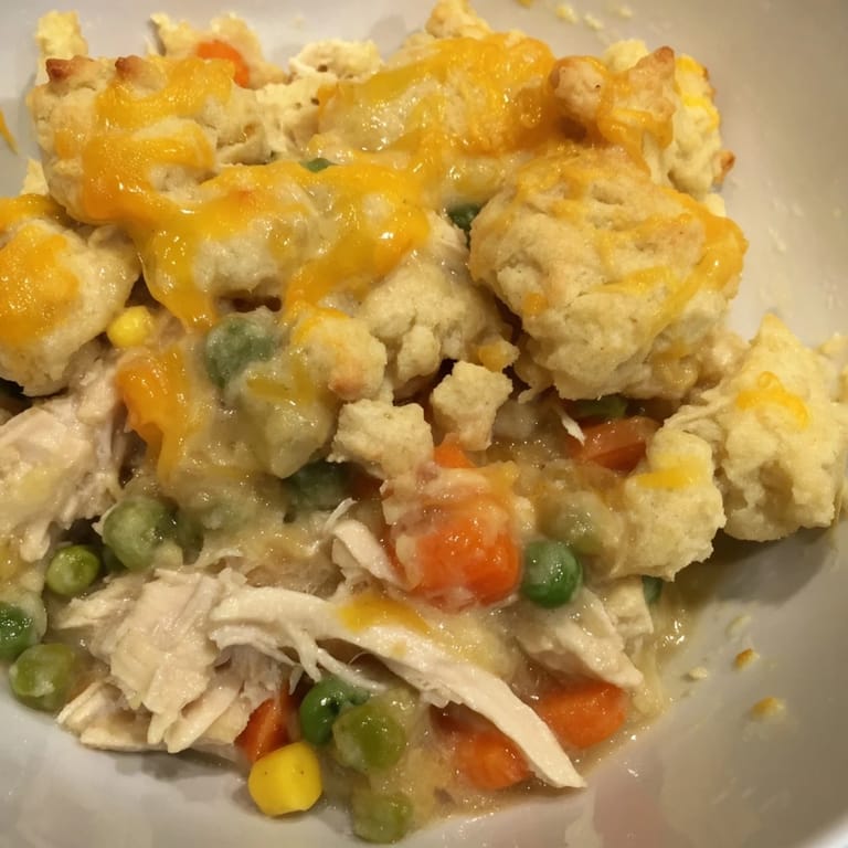 This one-pan chicken cobbler shows a bubbling filling under fluffy, freshly baked cheddar biscuits.