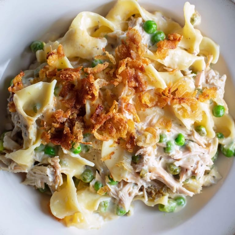 A bubbling baked tuna noodle casserole, the creamy base visible beneath the crunchy topping.