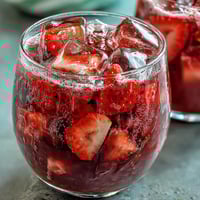 Vibrant pink strawberry açaí refresher with fresh fruit slices and ice, perfect for a refreshing summer beverage.